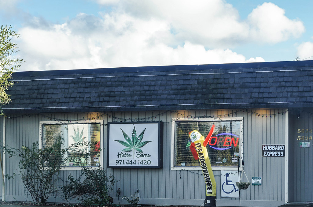 Dispensary storefront with a cannabis leaf sign and neon OPEN sign